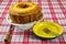 Homemade simple cake on white stand on table with white and red checkered tablecloth. Homemade common cake in front view