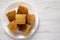 Homemade Sliced Cornbread Ready to Eat on a white plate over white wooden surface, top view. Flat lay, overhead, from above. Copy