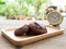 Homemade soft dark chocolate brownie cookies placed on a wooden plate on wooden table. Behind cookies have gold vintage alarm cloc