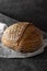 Homemade sourdogh whole round bread on dark background. Home baking concept