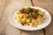 Homemade spaetzle, German egg noodles with cheese, roasted onions, bacon and breadcrumbs, served with parsley garnish on a white