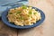 Homemade spaetzle served with parsley garnish on a blue plate and a rustic wooden table, traditional egg pasta in Schwaben,