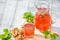 Homemade strawberry compote in glass decanter with pretzels on white wooden table in garden