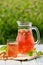 Homemade strawberry compote in glass decanter with pretzels on white wooden table in garden