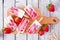 Homemade strawberry vanilla yogurt popsicles on a wood paddle board, overhead on rustic white wood