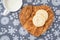 Homemade sugar cookies on a wood heart shaped cutting board, snowflake background, mug of milk