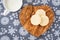 Homemade sugar cookies on a wood heart shaped cutting board, snowflake background, mug of milk