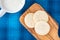 Homemade sugar cookies on a wood paddle shaped cutting board, blue plaid background, mug of milk