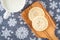 Homemade sugar cookies on a wood paddle shaped cutting board, snowflake background, mug of milk
