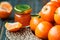 Homemade tangerine jam in glass jar with fruit around on a wooden table