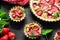 Homemade tarts with strawberry and rhubarb on black wooden background. Top view. Rustic style