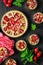 Homemade tarts with strawberry and rhubarb on black wooden background. Top view. Rustic style