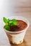 Homemade tiramisu, traditional Italian dessert in a plastic cup with mint leaf