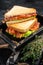 Homemade toasted BLT sandwich with bacon, tomato and lettuce in wooden tray. Black background. Top view