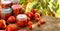 Homemade tomato preserves in glass jars and fresh tomatoes and herbs