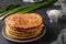 Homemade tortillas, located on a plate on a dark background, pictured green onions and sour cream