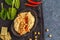 Homemade traditional hummus in a clay dish with spinach and crackers, dark background, top view. Healthy vegan food concept.