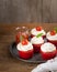 Homemade unsweetened savory appetizer cupcakes snacks with cream cheese frosting, tomato and fresh basil over wooden background,