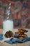 Homemade vegan oat cookie with banana, date and almond topped with chocolate placed on blue napkin next to a glass with milk