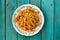 Homemade vegan pumpkin pilaf in colorful plate on turquoise tabl