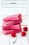 Homemade vegan raspberry coconut milk popsicles - ice pops - paletas with chia seeds on rustic white wooden background.