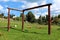 Homemade wooden outdoor playground swing with strong wooden frame in backyard surrounded with uncut grass and trees with family