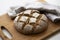 Homemade yeast sourdough rye wholegrain bread with Diamond Crosshatch scoring pattern on a wooden board with kitchen towel.