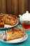 Homemade yummy apple pie, black tea in glass cup and white teapo