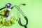 Homeopathic Healing herbs globule pills and a glass bottle on green background with Stethoscope and leaves