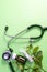 Homeopathic substance in white and brown bottle surrounded with Stethoscope and leaf on green background