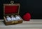 Homeopathy â€“ Close view of homeopathy medicine bottles in wooden classic box on wood surface with red heart on dark background