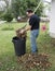 Homeowner Putting Leaves In A Trash Carrel