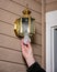 Homeowner replaces a light bulb in an outdoor light fixture