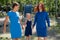 Homosexual lesbian couple hold daughter's hands. A girl walks with two mothers in the park. Two married women and a