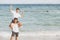 Homosexual portrait young asian couple riding the neck together with enjoy and fun on beach in summer