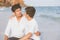 Homosexual portrait young asian couple sitting hug together on beach in summer