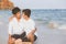 Homosexual portrait young asian couple sitting hug together on beach in summer