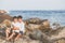 Homosexual portrait young asian couple sitting hug together on rock or stone in the beach in summer