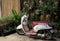 Honda`s small elegant motor scooter parked near a wall decorated with flowerpots with