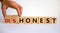 Honest or dishonest symbol. Businessman hand turns cubes and changes the word `dishonest` to `honest`. Beautiful white backgro