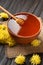 Honey with a dipper in a clay bowl and flowers on a dark wooden background