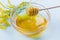 Honey drip from a wooden honey dipper in glass bowl on a blue background