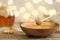 Honey dripping from dipper into bowl on table against blurred lights.