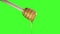 Honey dripping from honey dipper on green screen