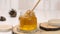 Honey dripping, pouring from honey dipper in a glass jar bowl