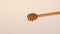 Honey falls on honey dipper on beige background