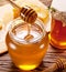 Honey flowing into glass can from wooden stick.