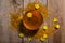 Honey in the glass bowl, pollen and yellow flowers around it