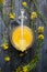 Honey in glass jar with dipper and fresh rapeseed blooming on blue wooden background