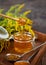 Honey in a glass jar with a wooden spoon. Still life on a wooden table with yellow flowers Goldenrod. Healthy sweet food